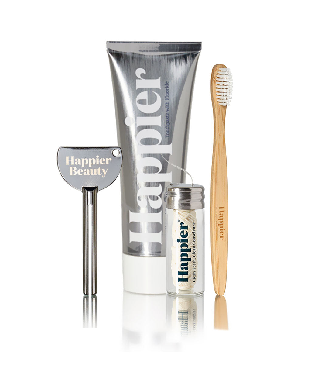 Happier Dental hygiene essentials: Bamboo toothbrush, Happier toothpaste, squeeze ksy and floss.